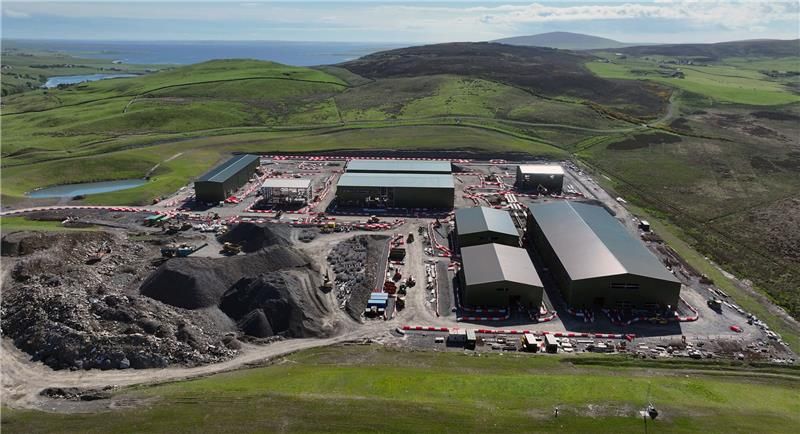Aerial view of the Finstown Substation construction site showing large industrial buildings, earthworks, and surrounding rolling green hills in Orkney.